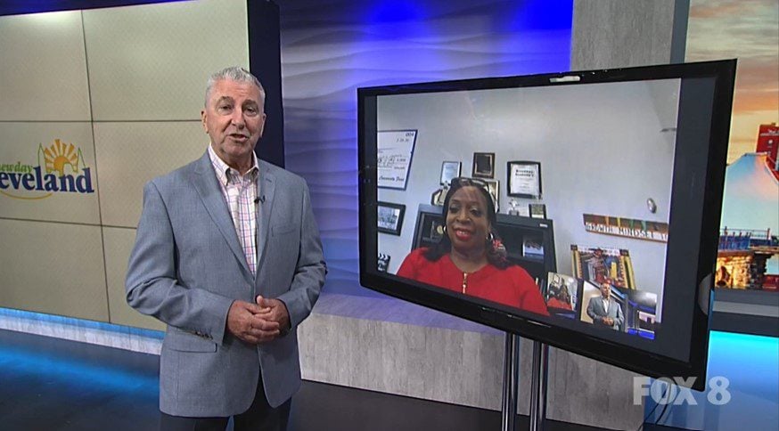 Adult man in studio next to screen with adult woman on video call.
