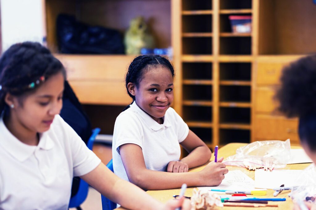 Smiling students drawing in an art class.